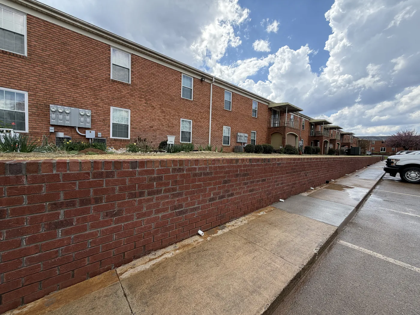 Brick retaining wall with building facades and landscaping at Chateau Rivera