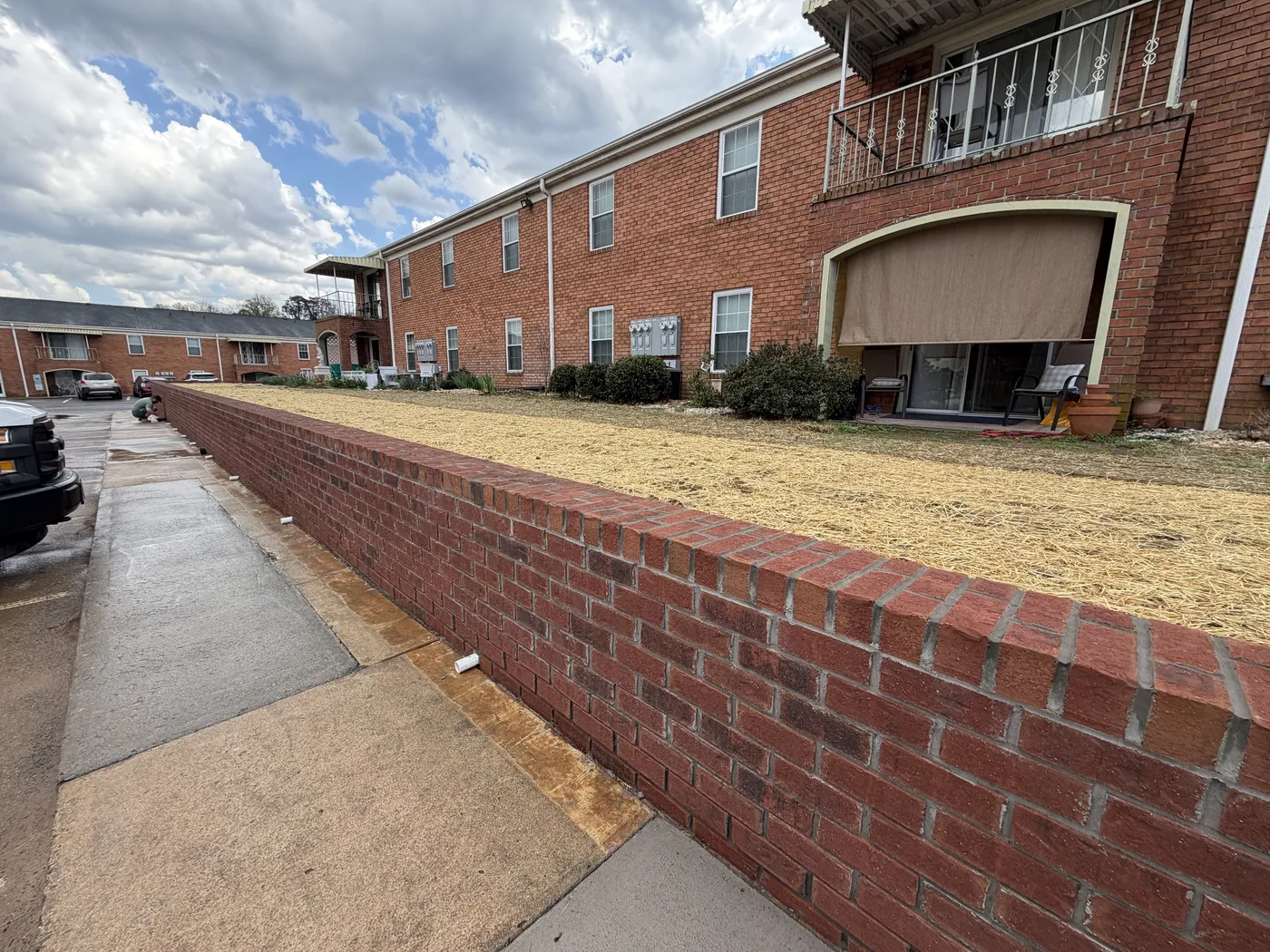 Front entrance view of apartment building with new brick retaining wall and steps