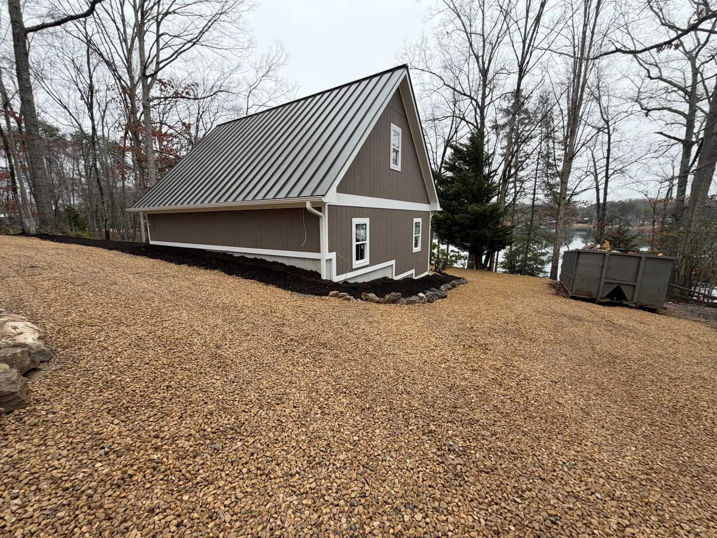 Rear view of garage with mulch beds and gravel driveway